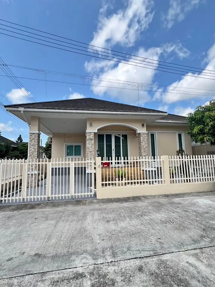 Charming single-story house with a fenced yard and modern exterior design under a clear blue sky.