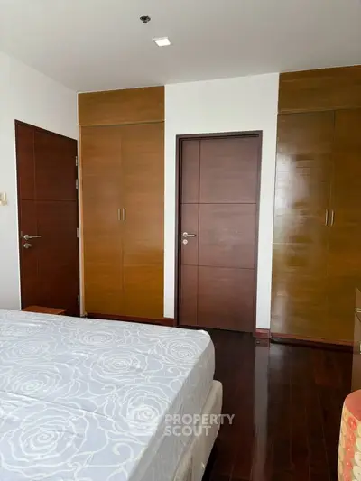 Spacious bedroom with wooden closets and elegant flooring