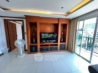 Spacious living room with elegant wooden entertainment center and balcony view.