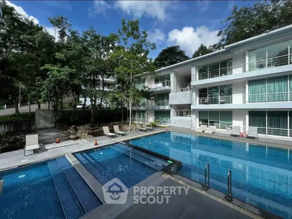 Luxurious modern apartment complex with a stunning outdoor pool and lush greenery.