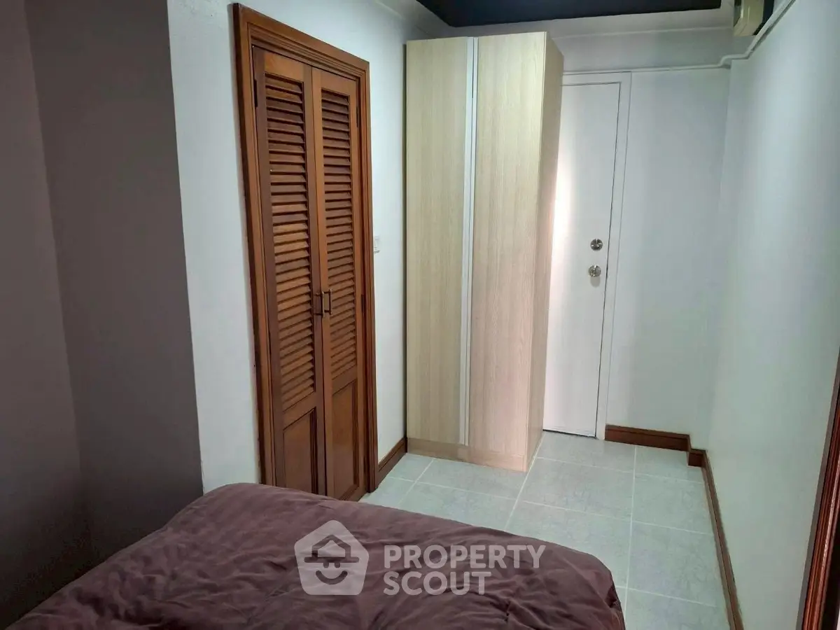 Cozy bedroom with wooden closet and modern wardrobe, perfect for compact living.