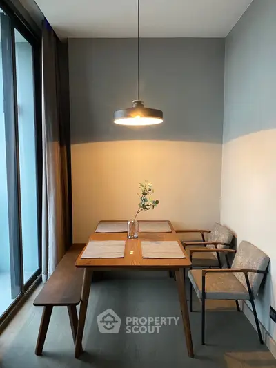 Modern dining area with wooden table, chairs, and pendant light, perfect for cozy meals.