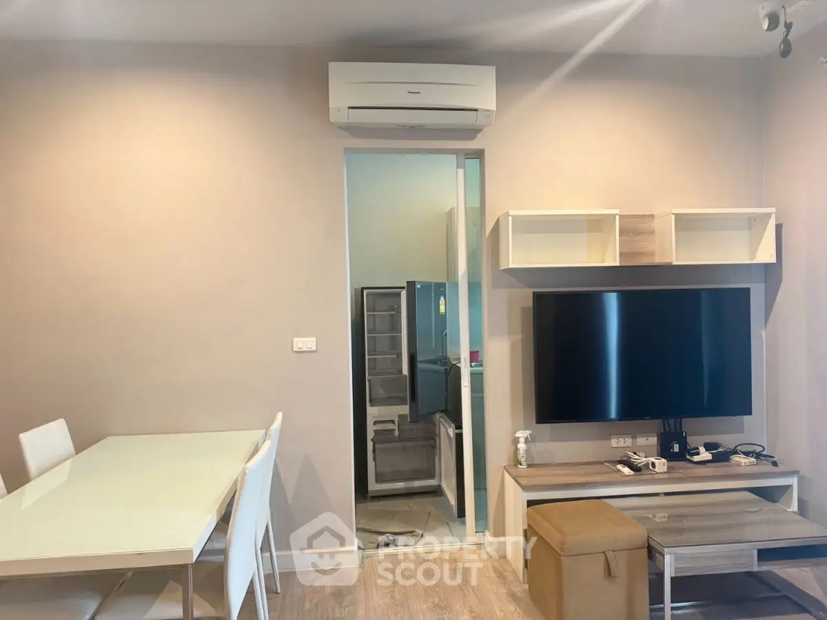 Modern living room with air conditioning and sleek furniture, featuring a dining area and wall-mounted TV.