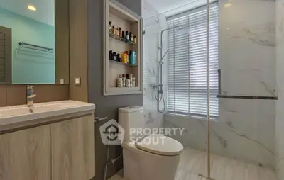 Modern bathroom with glass shower, built-in shelving, and sleek fixtures.