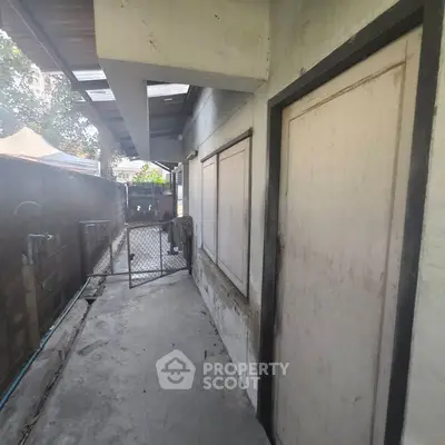 Outdoor view of a residential property with gated entrance and concrete pathway.