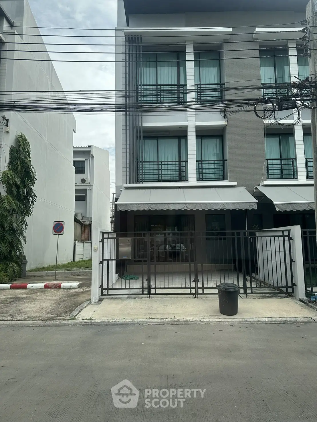 Modern three-story townhouse with gated entrance and contemporary design in urban setting.