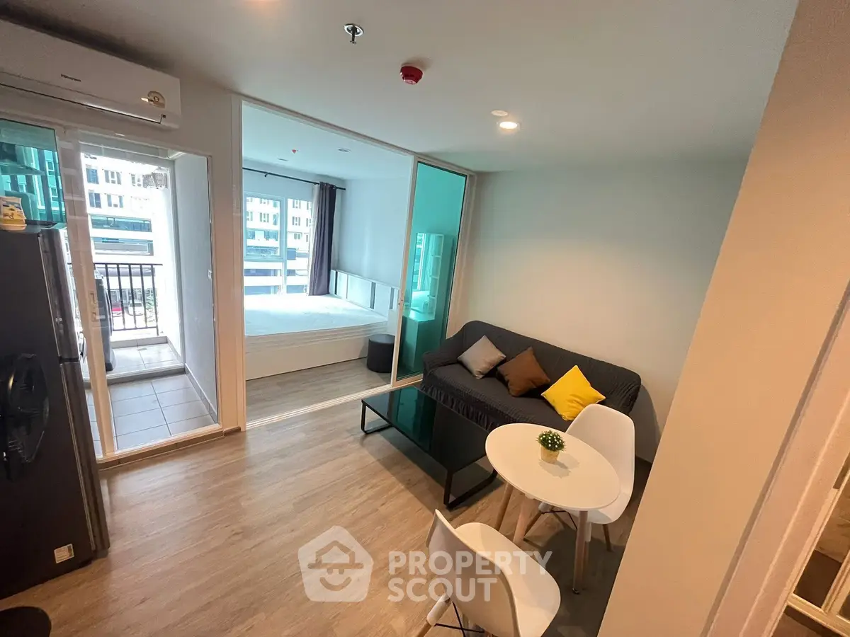 Modern studio apartment with open layout, featuring a cozy living area and a balcony view.