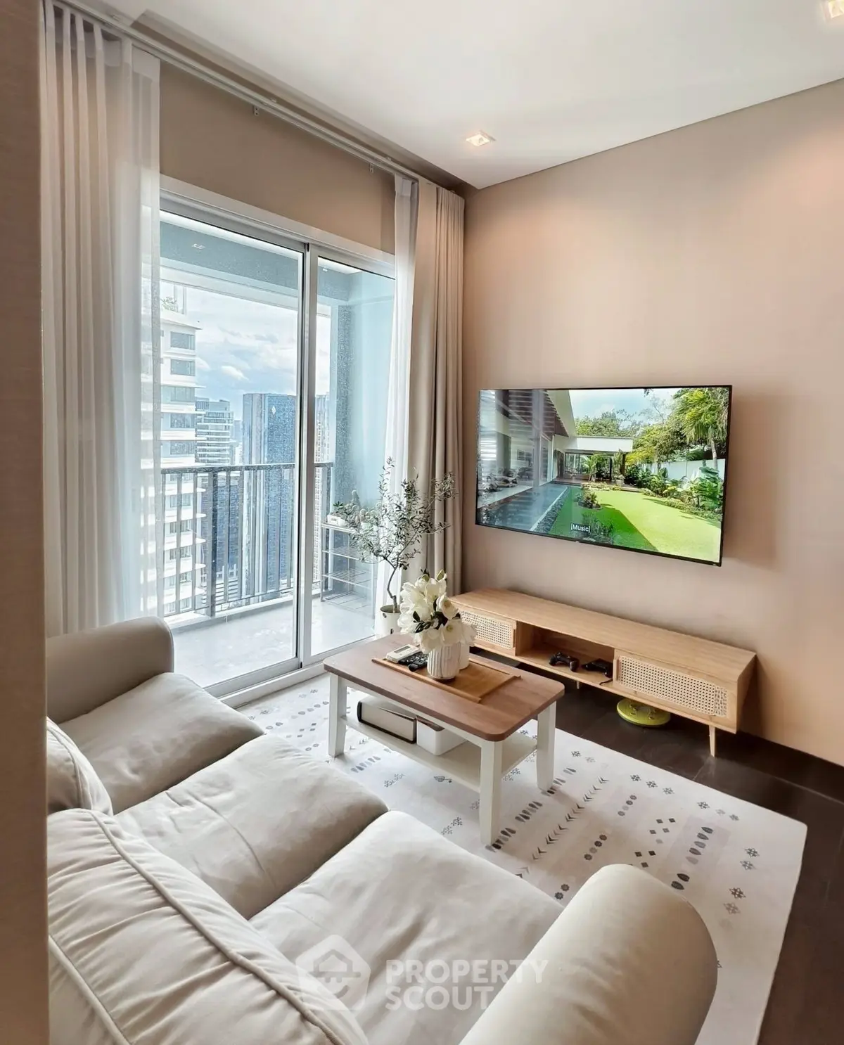 Modern living room with cozy sofa, large TV, and balcony view in high-rise apartment.