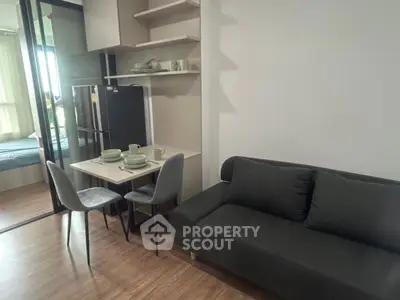 Modern compact living room with dining area and view into bedroom, featuring sleek furniture and natural light.