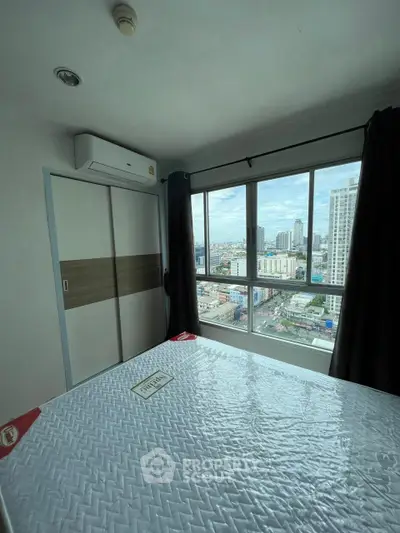 Modern bedroom with city view and large window in high-rise apartment.