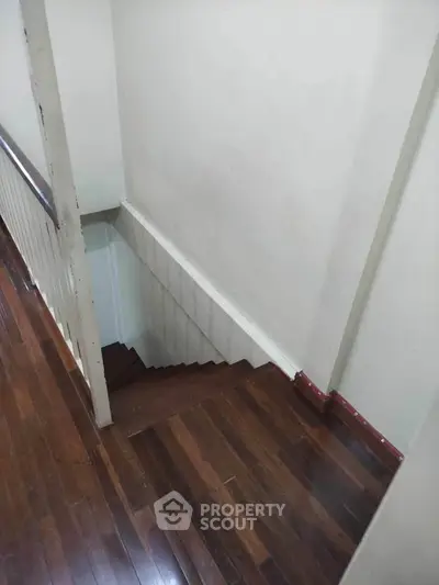 Wooden staircase with railing in a residential property, showcasing classic interior design.