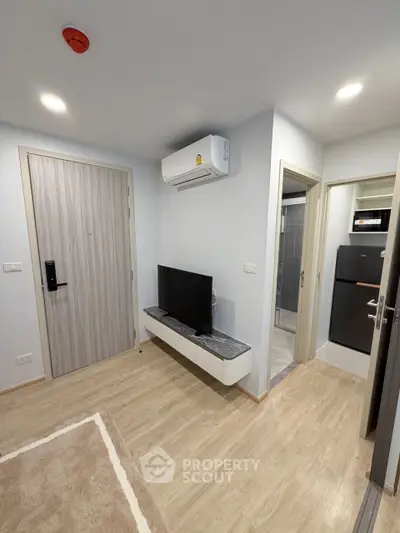 Modern apartment entryway with sleek TV setup and air conditioning, showcasing efficient use of space.