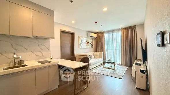 Modern open-layout living room with kitchen, featuring sleek design and natural light.