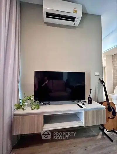 Modern living room with air conditioning, TV, and guitar, perfect for relaxation and entertainment.