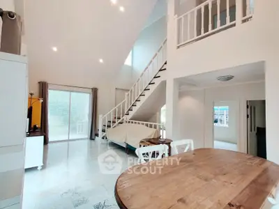 Spacious open-plan living area with high ceilings and elegant staircase