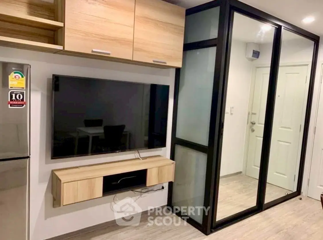Modern living room with sleek TV setup and glass partition in stylish apartment.