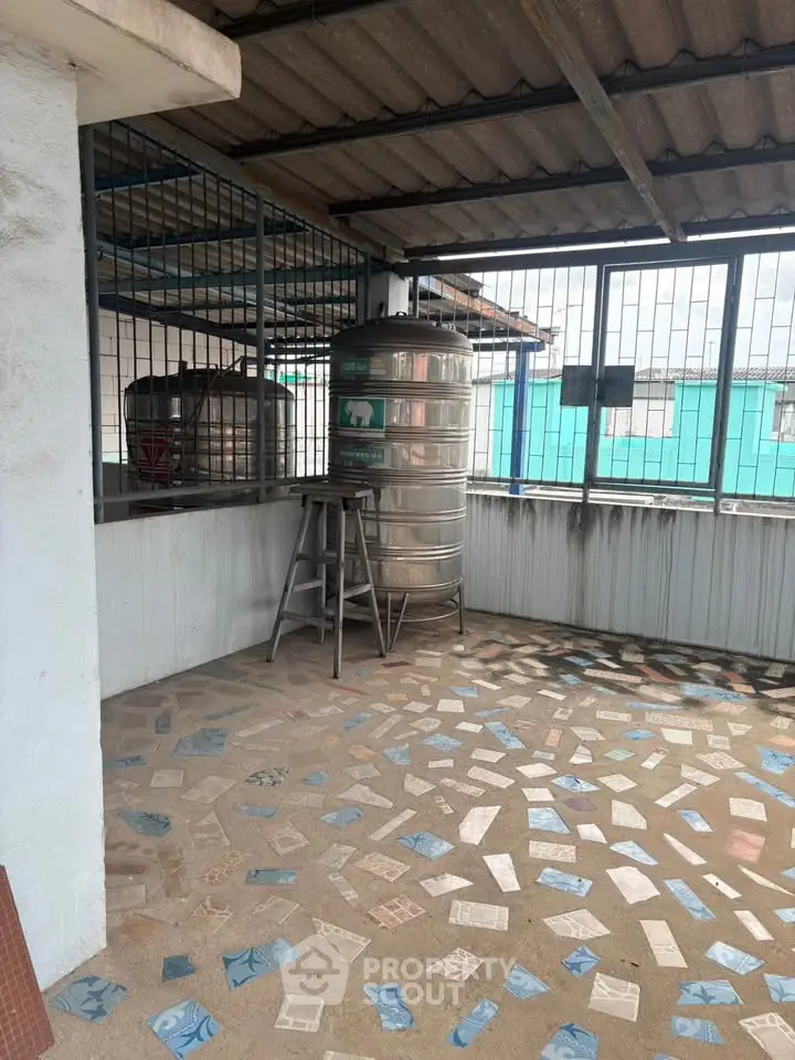 Spacious rooftop area with water tanks and tiled flooring, ideal for utility and storage.