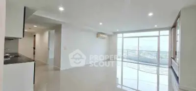 Spacious modern living room with large windows and balcony offering stunning city views.