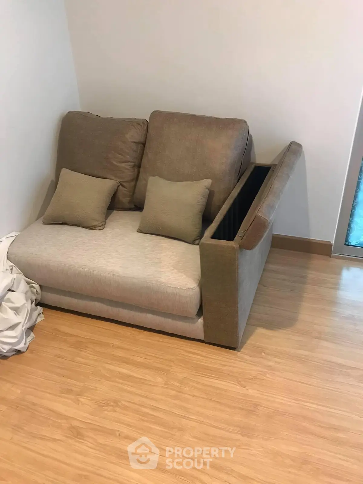Cozy living room corner with modern sofa and wooden flooring, perfect for relaxation.