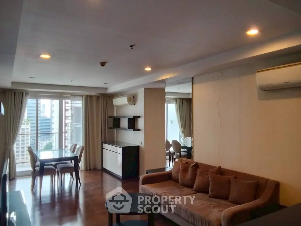 Spacious living room with modern furnishings and city view balcony in luxury apartment.