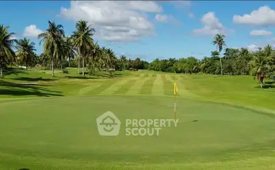 Luxurious golf course view with lush greenery and palm trees under a clear blue sky.