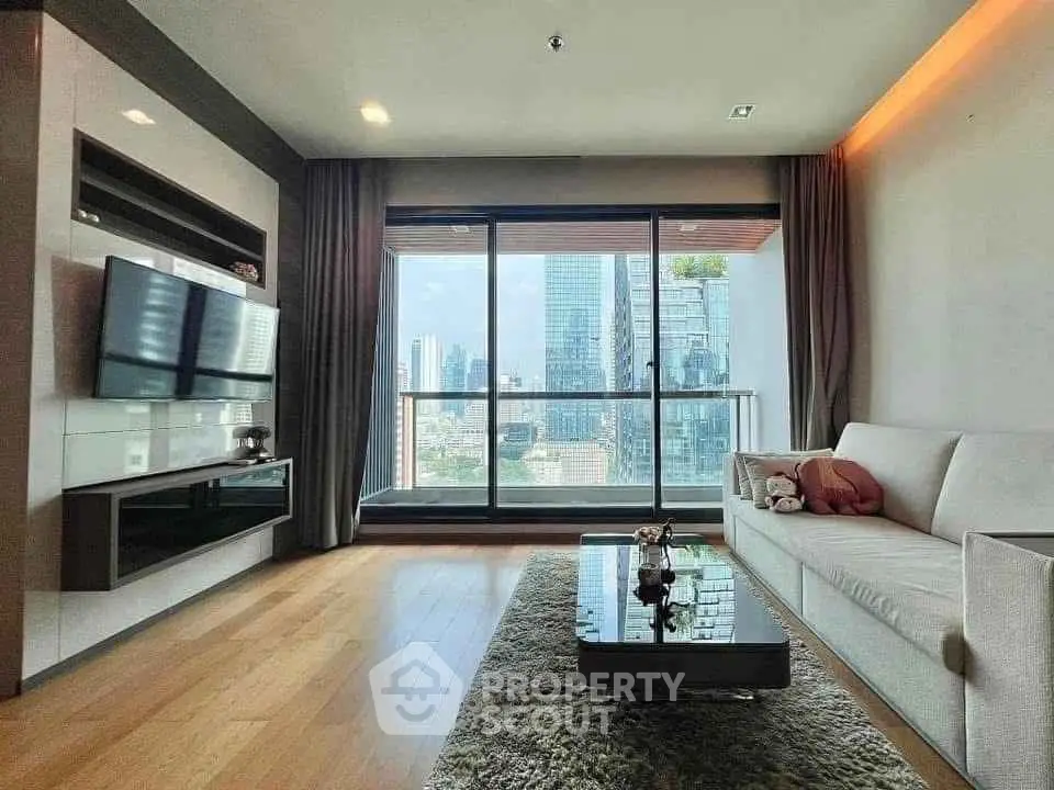 Modern living room with city view, featuring sleek furniture and large windows for natural light.
