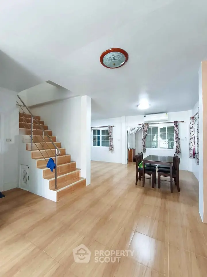 Spacious open-plan living area with wooden flooring and modern staircase.