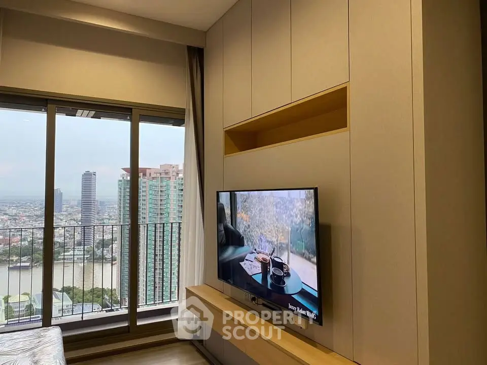 Modern living room with large window and city view, featuring a wall-mounted TV and sleek storage.