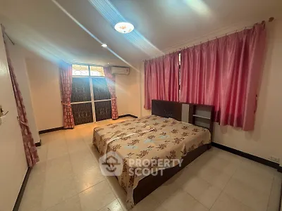Spacious bedroom with large windows and elegant curtains in a cozy apartment.
