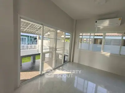 Bright room with large windows and air conditioning, overlooking a modern outdoor space.