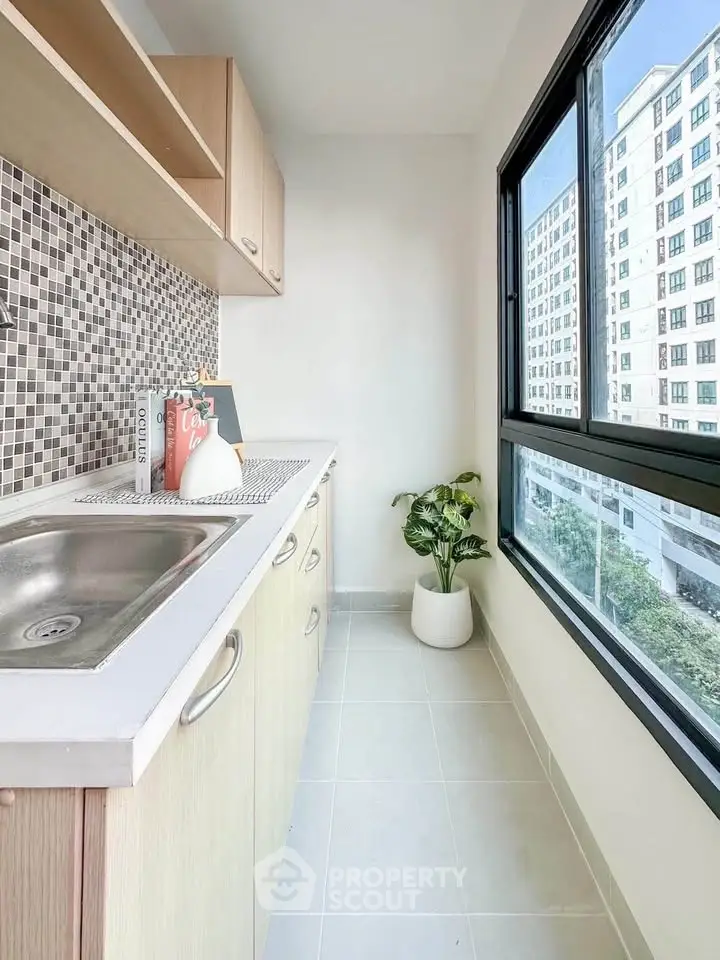 Bright kitchen with modern cabinetry and large window view in urban apartment