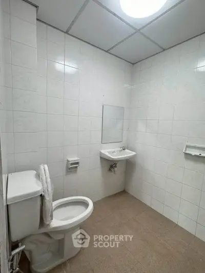 Minimalist bathroom with white tiles and basic fixtures