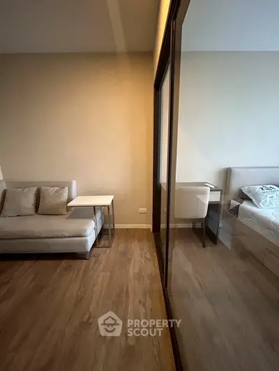 Modern apartment interior with cozy living area and bedroom separated by glass partition.