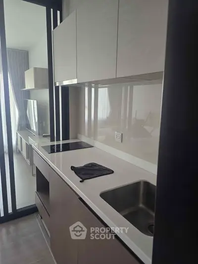 Modern kitchen with sleek cabinetry and built-in stovetop in a contemporary apartment.