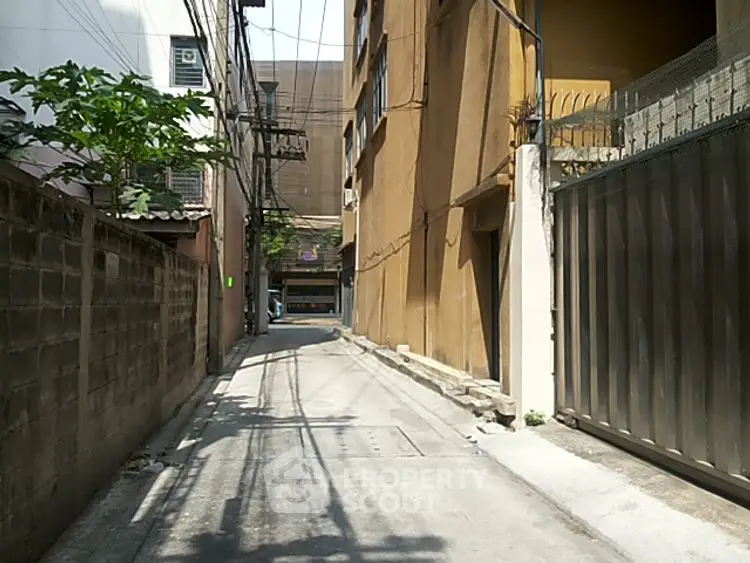Narrow alleyway beside residential building with gated entrance