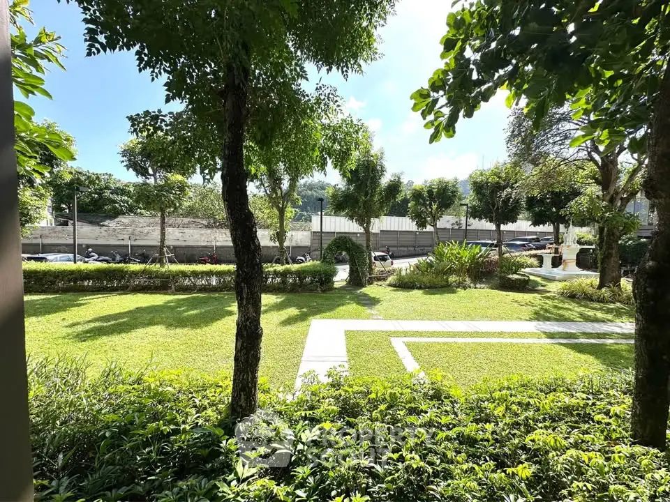 Lush green garden with trees and pathway in a serene residential area.