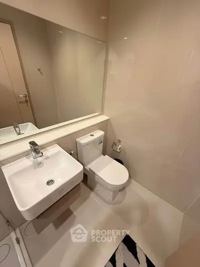 Modern bathroom with sleek fixtures and large mirror in a contemporary apartment.