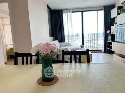 Modern living room with large windows and city view, featuring elegant decor and natural light.