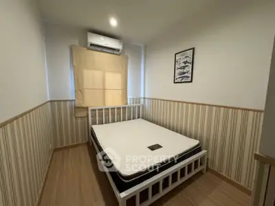 Cozy bedroom with striped wallpaper and air conditioning, featuring a comfortable bed and wooden flooring.