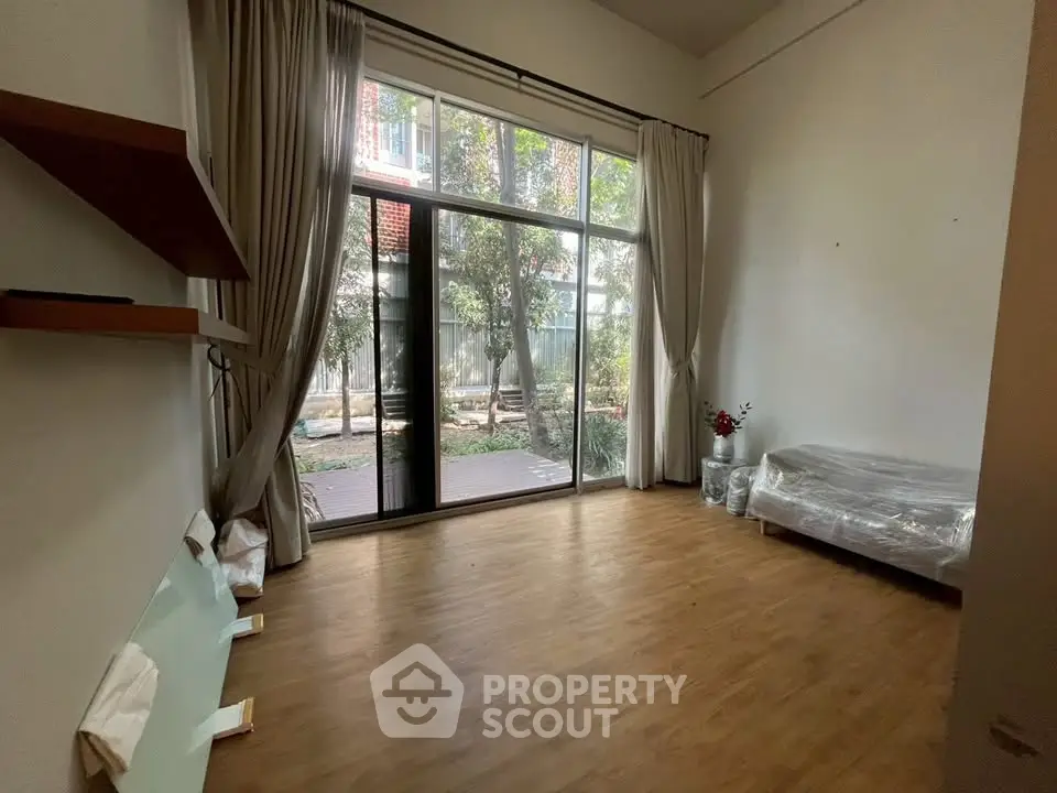 Spacious living room with large windows and garden view, perfect for relaxation.