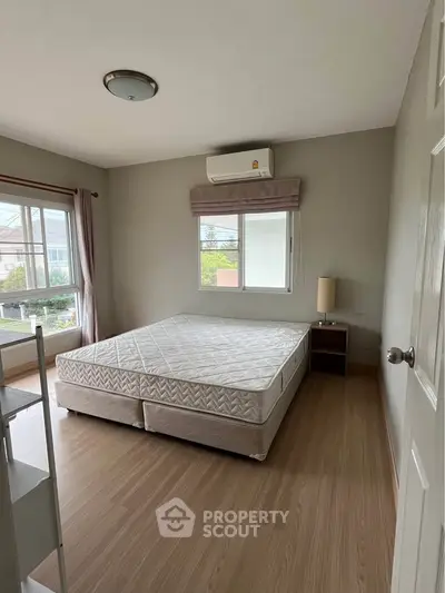 Spacious bedroom with large window and natural light, featuring a comfortable bed and modern decor.