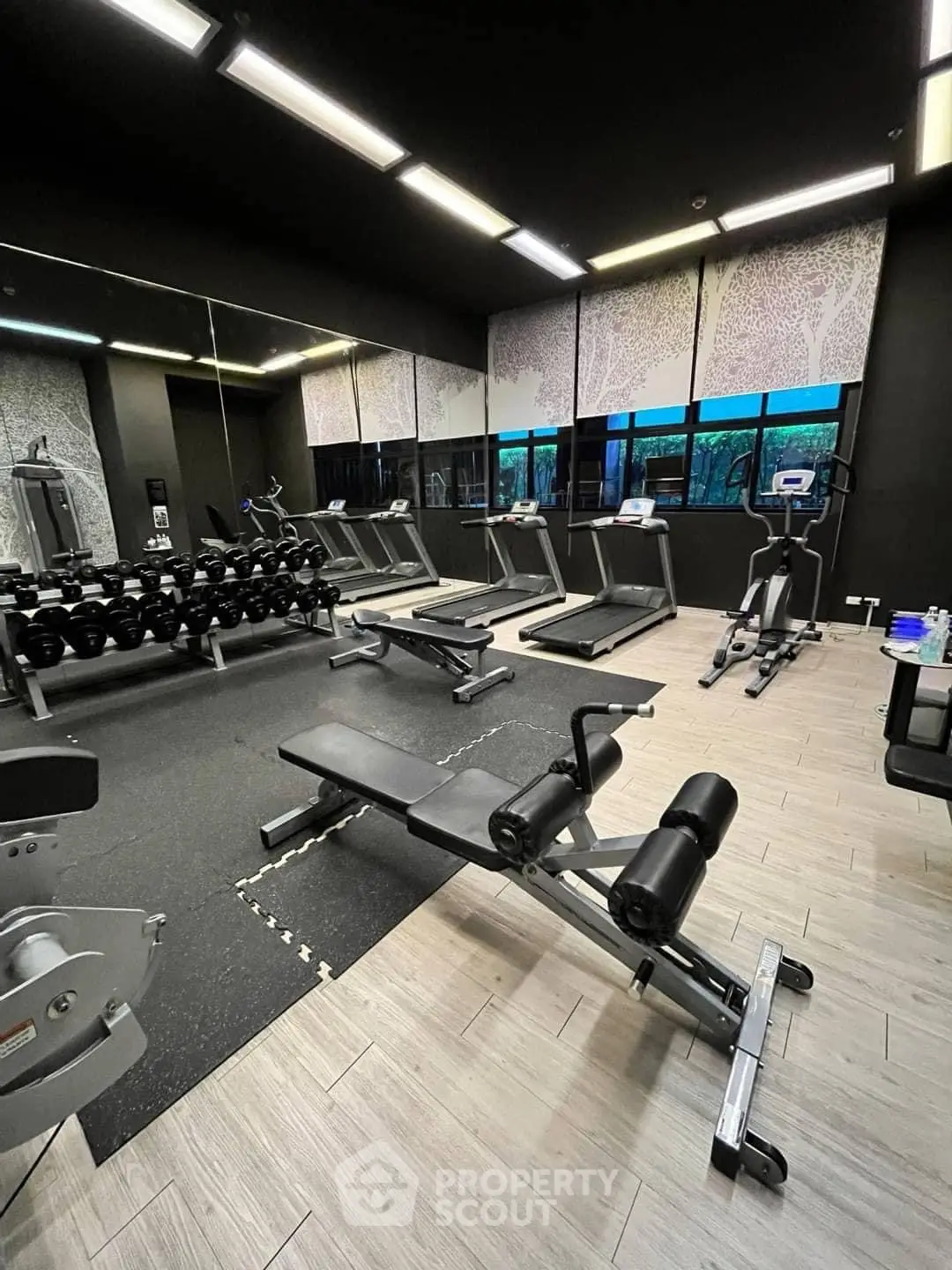 Modern gym with state-of-the-art equipment and large mirrors in a luxury building.