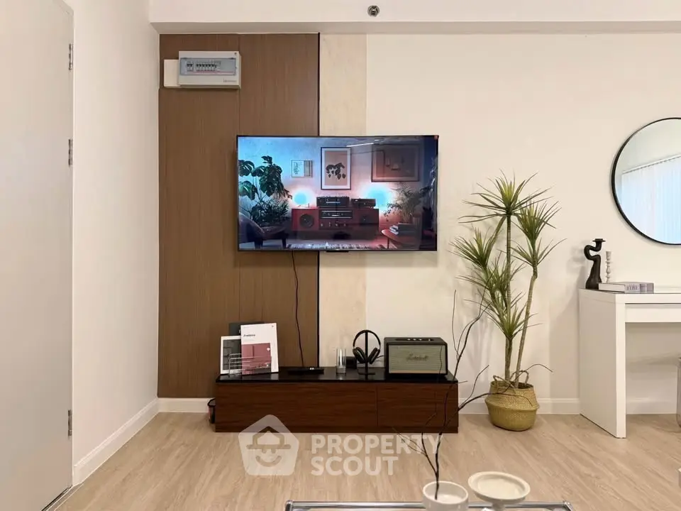 Modern living room with stylish decor and wall-mounted TV, featuring a sleek wooden cabinet and indoor plants.