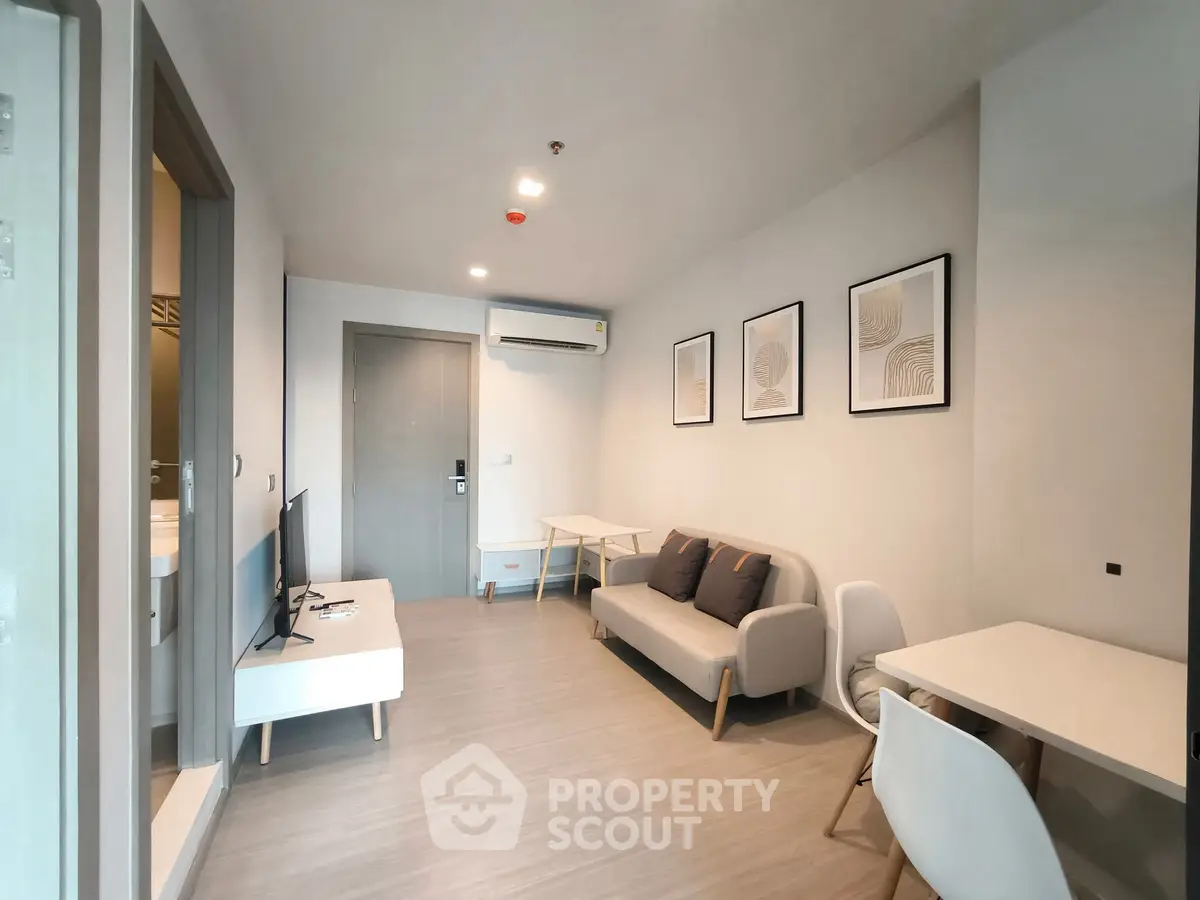 Modern living room with minimalist decor, featuring a cozy sofa, wall art, and a sleek TV setup.