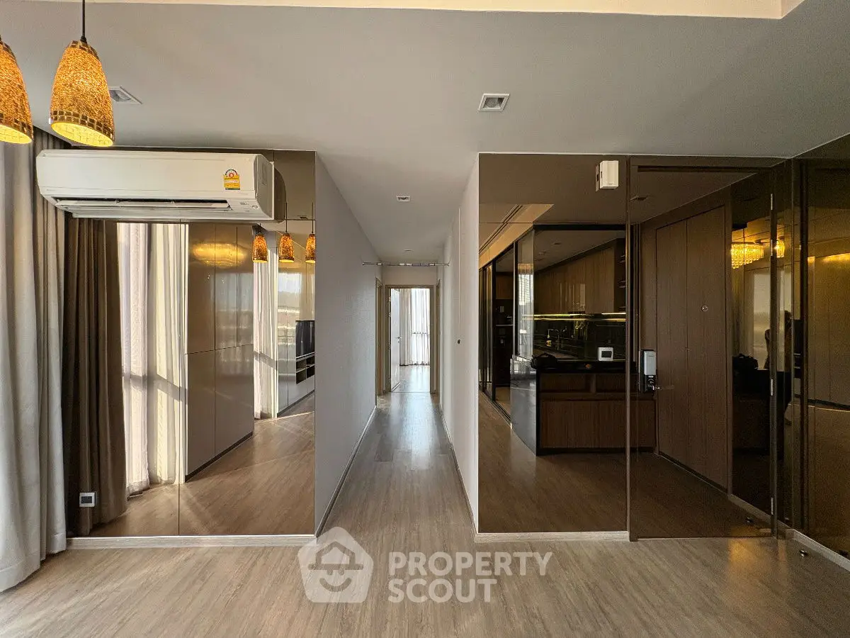 Modern apartment hallway with mirrored walls and air conditioning unit.