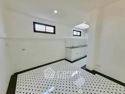 Spacious kitchen with modern black and white tiled flooring and ample natural light.