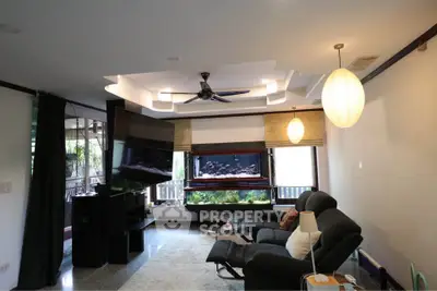 Spacious living room with modern ceiling design and large windows overlooking greenery.