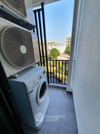 Compact balcony with washing machine and air conditioning units, offering a city view.