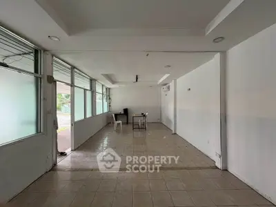 Spacious empty room with tiled floor and large windows, ideal for customization.