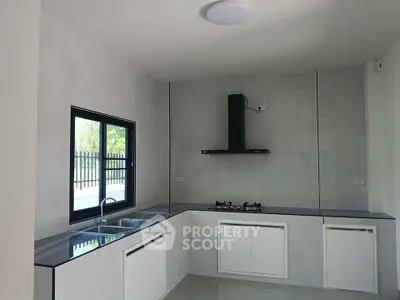 Modern kitchen with sleek countertops and gas stove in a bright, minimalist design.